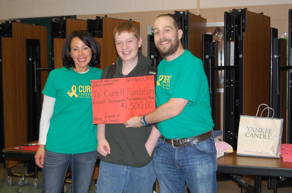 Sophomore Kyle Krawiec hands off the check raised for the Cure it Foundation to Dr. Jason Canner.