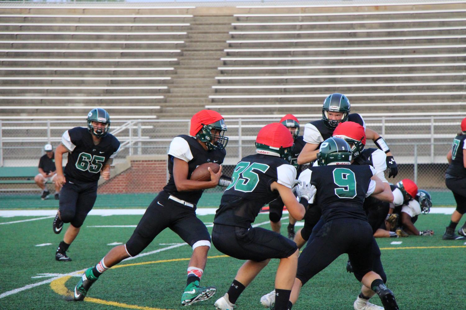 Varsity offense scrimmages against Varsity defense. The red caps help distinguish the teams.