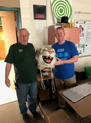 Jeff Pesevanto, custodian, passes the Wildcat Head to Darren Kobliska, history teacher.