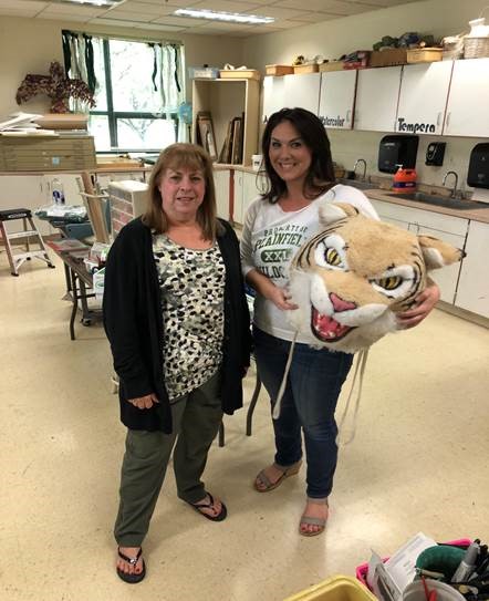 Diane Milligan, secretary, passes the Wildcat head to Lindsey Brown, art teacher.