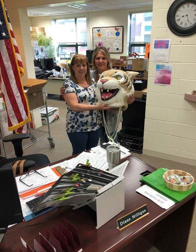 Kathy Rose, special ed secretary, passes the Wildcat head to Diane Milligan, main office secretary.