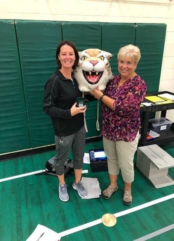 Judy Vihnanek passes the wildcat head to Jen Tomczak, PE department chair