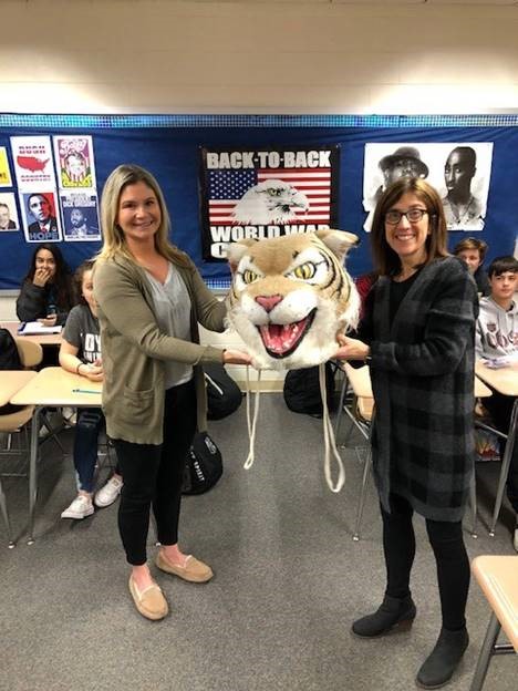 Karen Seeberg, ELL teacher, passes the Wildcat head to Nicki Koleno, Social Studies teacher.