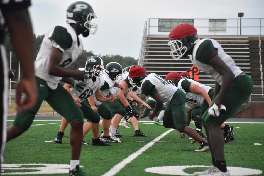 The varsity squad faces off against each other in the annual Green and White Night scrimmage, one side wearing red caps since the uniforms are the same.
