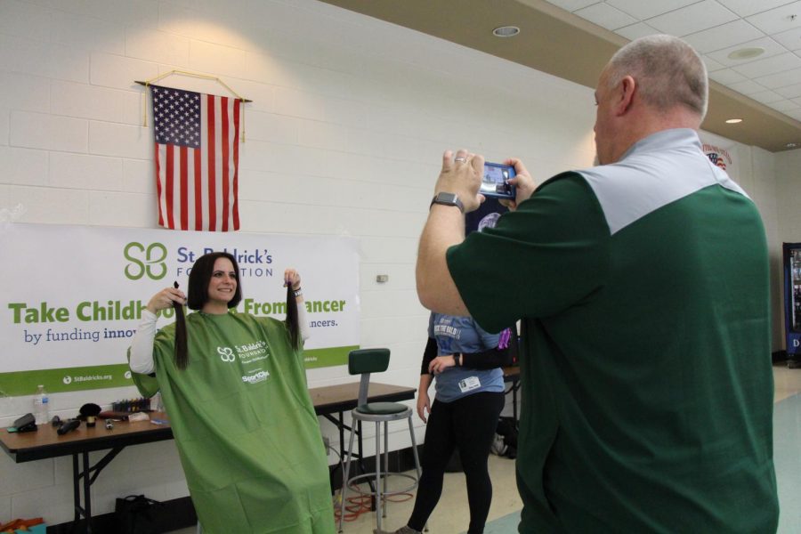 Krusz holds up her chopped locks for a picture by her husband Mark Krusz, Athletic Director.