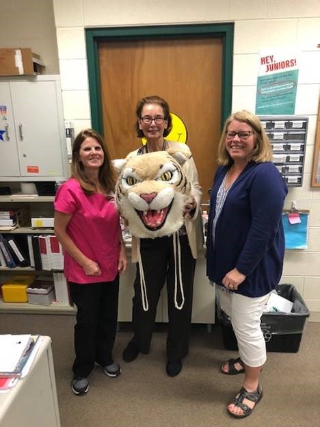 Audrey Stein, bookkeeper, passes the Wildcat award to Ruth Brick and Susan Wolf, nurses.