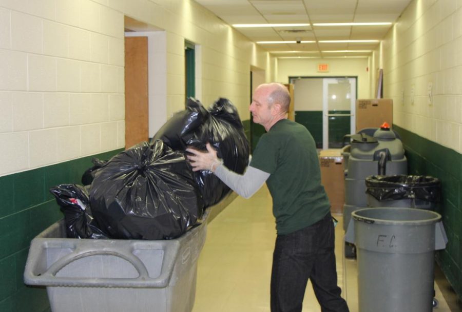 Kevn Codo, custodian,  dumps bags of trash into trash carts each night to have empty cans for the next day.