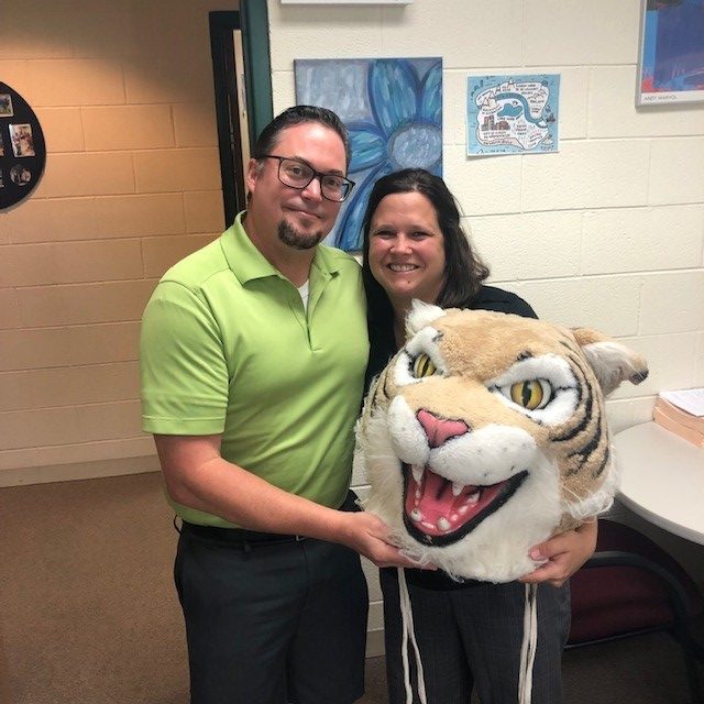 PE teacher Tim TORKELSON passes the Wildcat award to counselor Jen Giorgetti.
