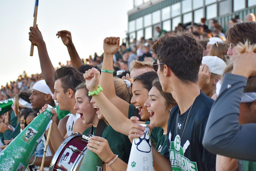 Students cheer on the football team as they play a game of scrimmage. 