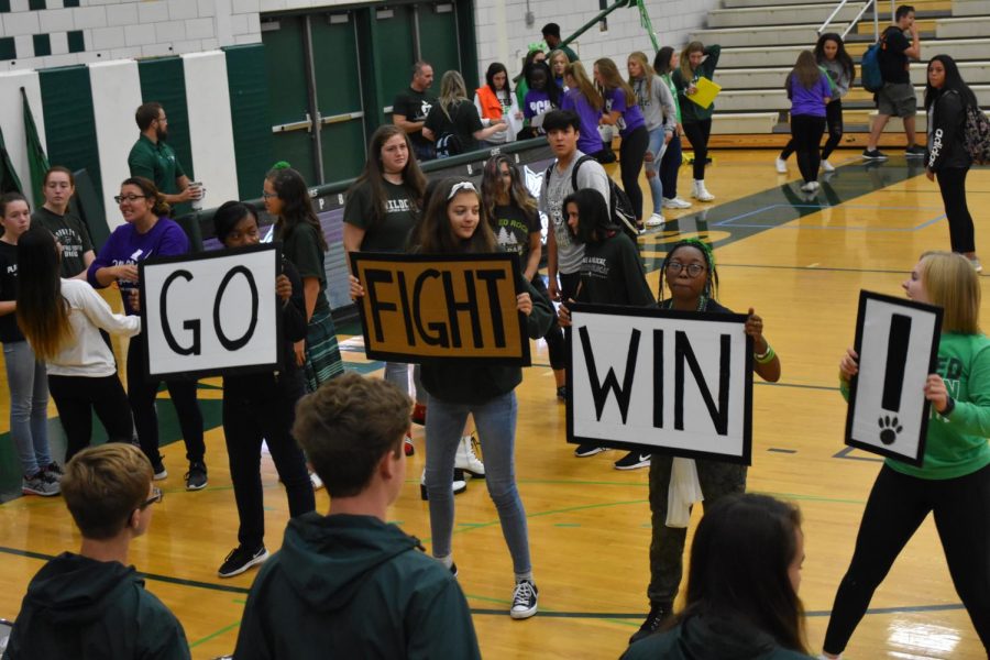 Band Drum Majors Tiara Guider, senior; Paige Gieseke, senior; Jade Price, junior; and Georgia Sigler, senior lead the band in a song while dancing with signs to keep rhythm.