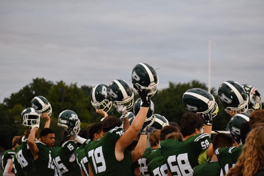 The players raise up their helmets before starting the first quarter. 