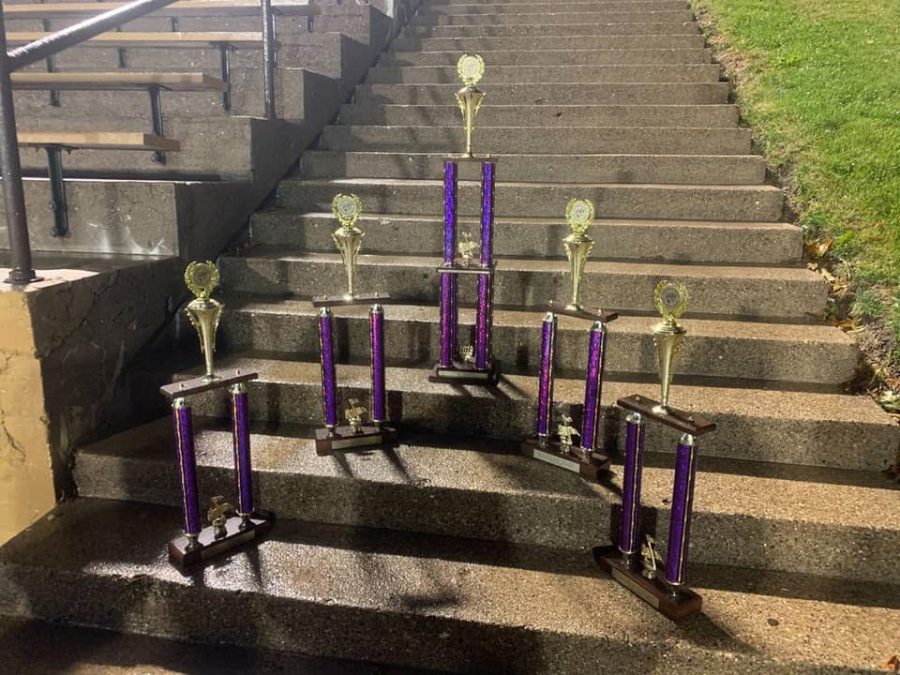 Trophies labeled Best Winds, Best Percussion, Best Auxiliary, Best Drum Majors, and 1st in class 4A sit on a stair in the stadium at Western Illinois University on Oct 26.