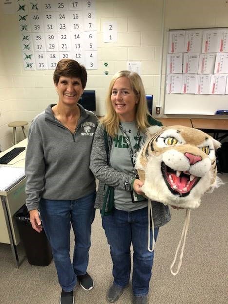 Linda Hogan, media specialist, passes the Wildcat Award to Kristen Clark, math teacher.