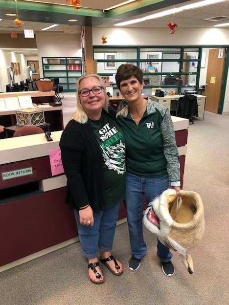 Charlotte Kics, special ed teacher, passes the Wildcat Award to Linda Hogan, media specialist.