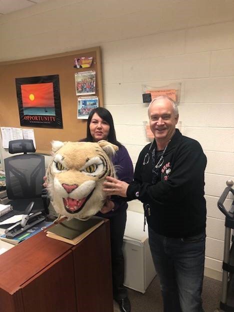 Ken McBeth, media specialist, passes the Wildcat Award to Colleen Cundari, administrative assistant.