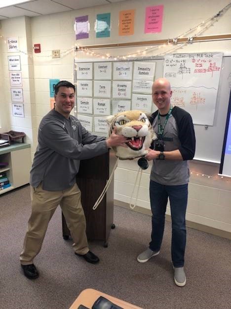 Kevin Fitzgerald, history teacher, passes the Wildcat head to Chris Wells, special ed teacher.