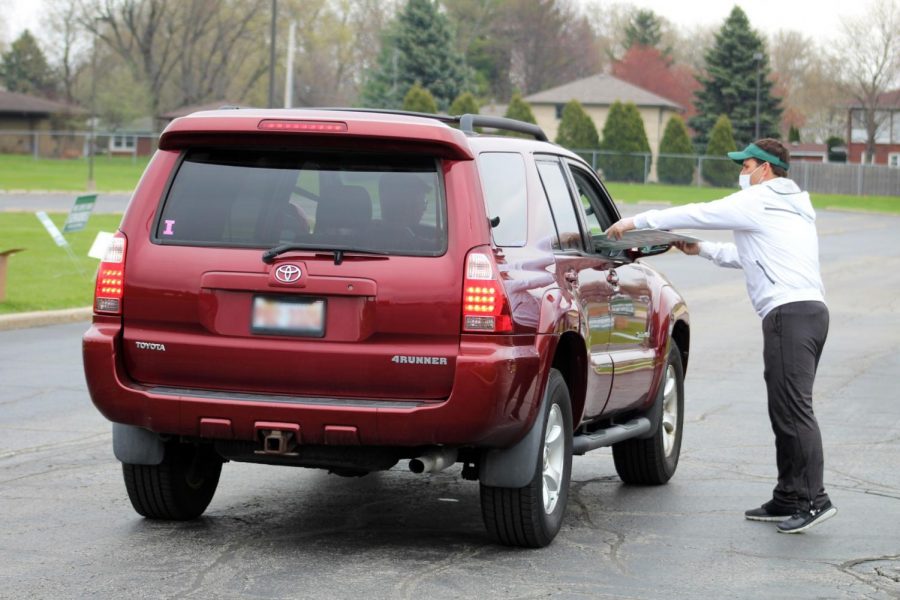 Plainfield High School-Central Campus Principal Dave Stephens hands a yard sign to a senior student on during curbside pickup on Thursday, April 23, 2020. The high school provided the signs to show support for the Class of 2020 during the COVID-19 pandemic.