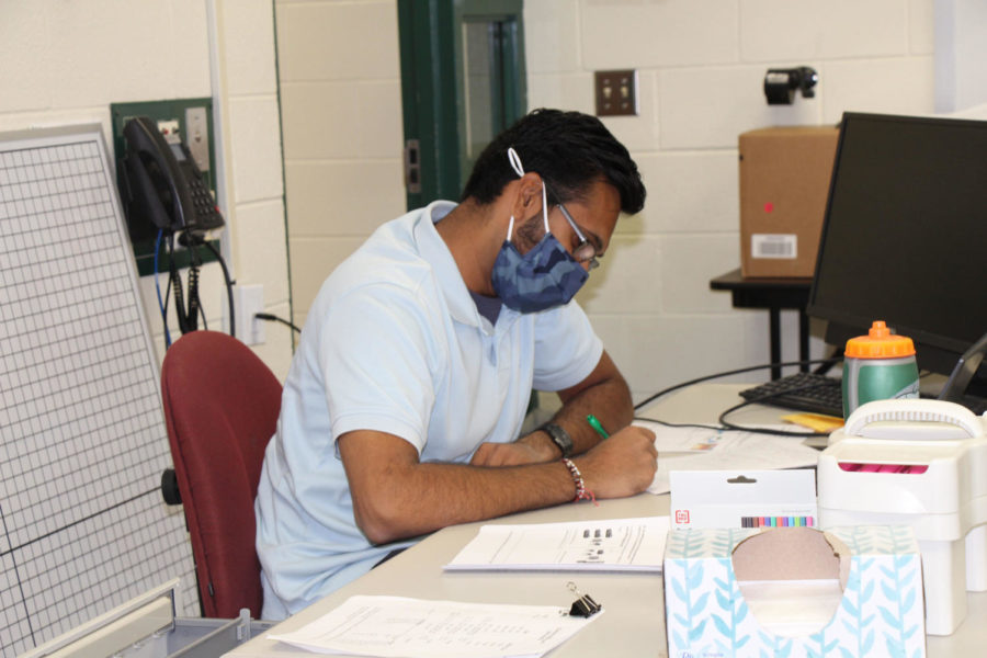 Milan Bhatt, math teacher, wears his mask while he grades students’ assignments after class.