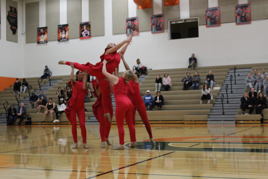 The poms team lifts Emma Backstrom, sophomore, during conference. The same routine earned them a spot at state.