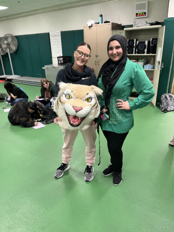 Baraa Rashid, English teacher, passes the Wildcat award to Kaitlyn Polakovic, PE teacher.