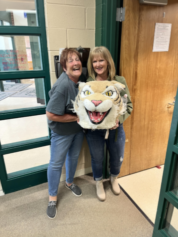 Trish Stoner passes the Wildcat award to Pat Maher, campus monitor.