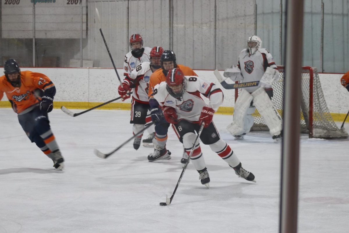 Owen Peszynski, junior, steals the puck from opposing team’s players and races across the ice.