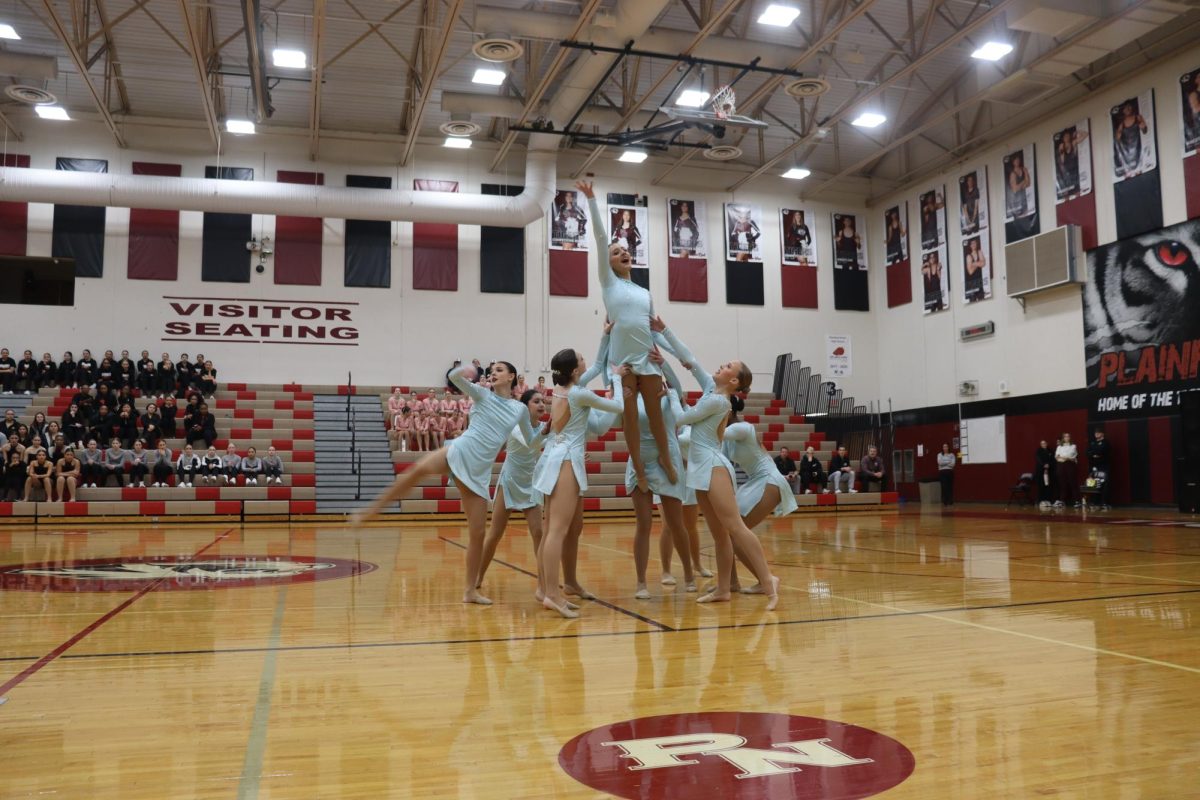 The poms team lifts Camila De La Torre, senior, during the Plainfield North invite on January 15, showcasing unity and strength.