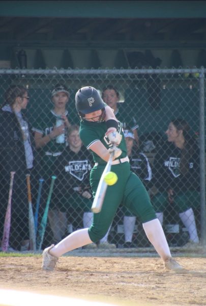 Junior Meave Carlton connects with the pitch, driving the ball
as her teamates watch from the dugout
