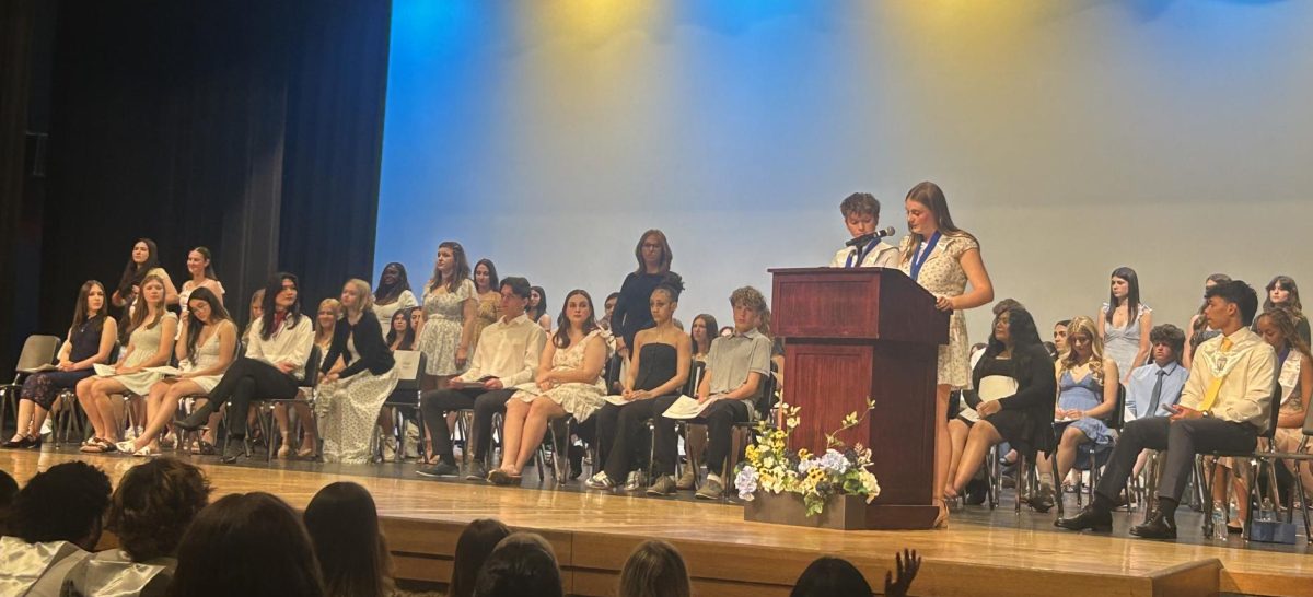 NHS Vice President Grace Newberry, senior, inducts the incoming NHS officers, by having them stand as she reads the names